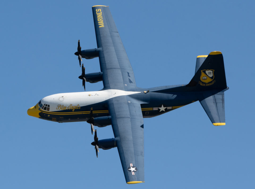 A U.S. Navy C-130J Hercules, nicknamed “Fat Albert,” soars in flight as the support aircraft for the U.S. Navy Blue Angels demonstration team. Painted in the squadron’s signature blue and yellow livery with “Blue Angels” script on the fuselage, the four-engine transport aircraft plays a vital role in logistics and support during air show performances.