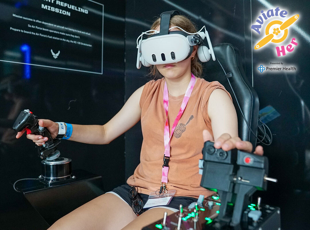 Participant using a virtual reality flight simulator with joystick controls during the Aviate HER STEM experience at the CenterPoint Energy Dayton Air Show, presented by Premier Health.