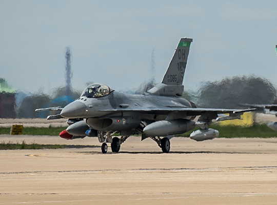 USAF F-16 Fighting Falcon taxiing on runway with heat blur behind