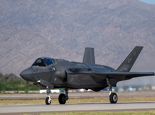 USAF F-35A Lightning II taxiing on runway with desert mountains in background