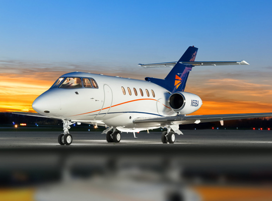 Hawker 800 business jet parked on runway at sunset