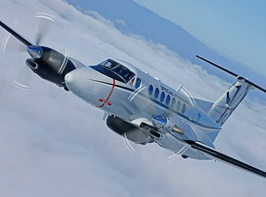 U.S. Navy King Air 350 aircraft in flight banking over clouds