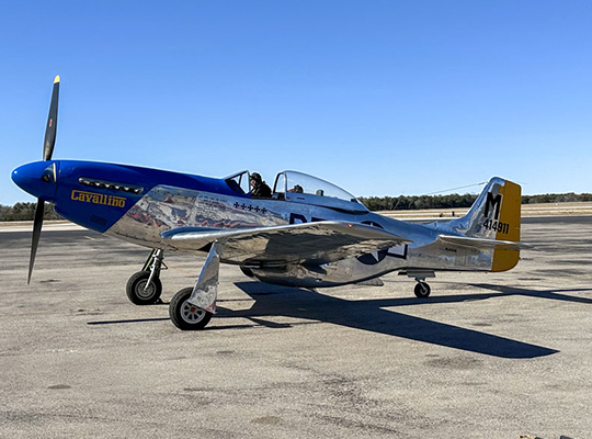 P-51 Mustang parked on tarmac with polished metal finish
