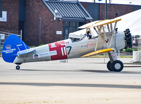 Stearman biplane parked on ramp near building