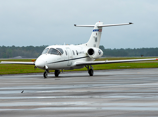 USAF T-1 Jayhawk on wet runway with landing lights visible